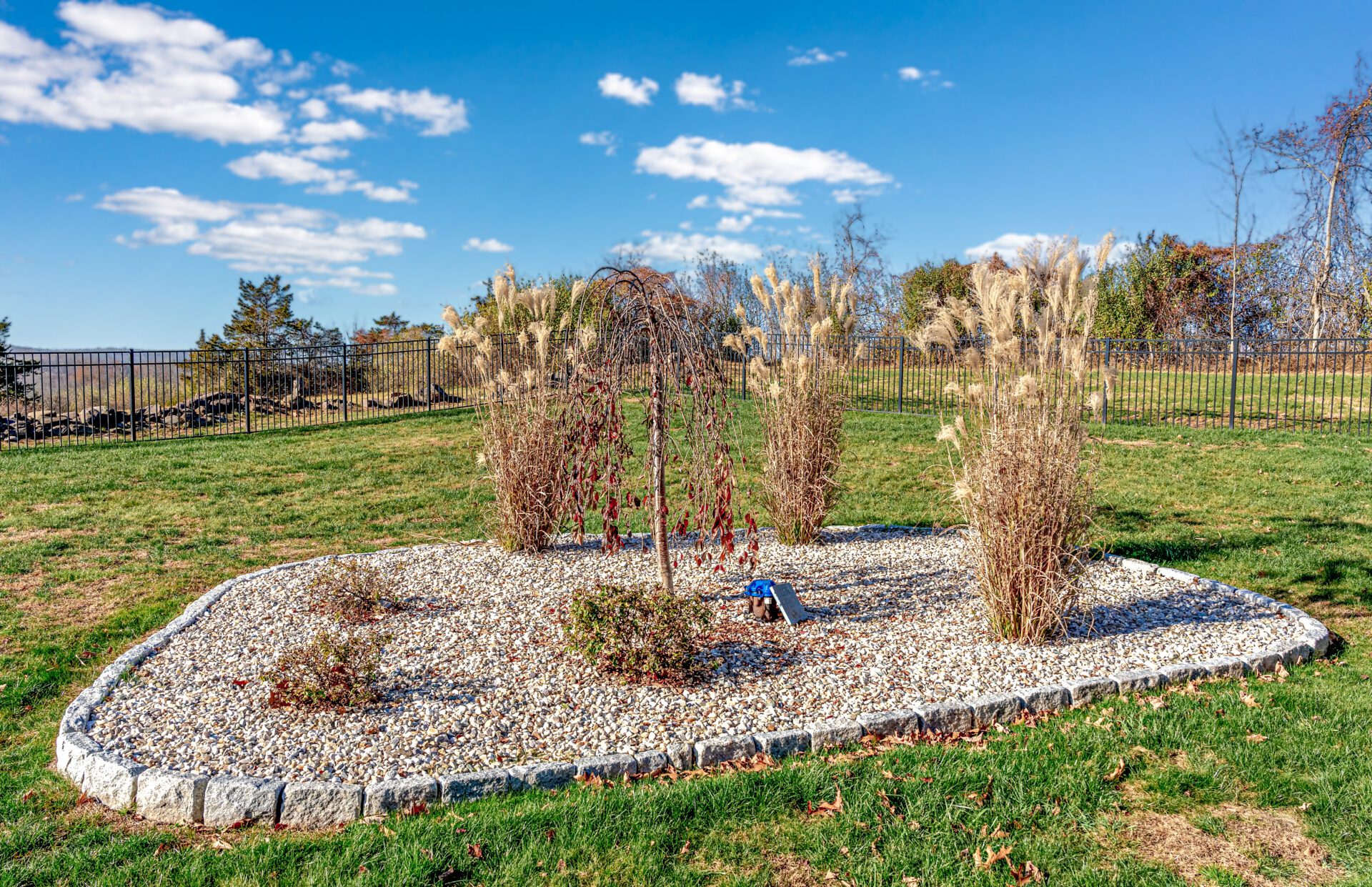 gravel planting containg bushes surounded by a rock barrier.